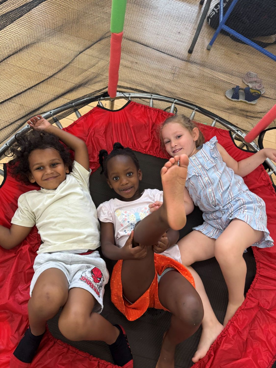 Three children lying on a trampoline laughing at the end of the day