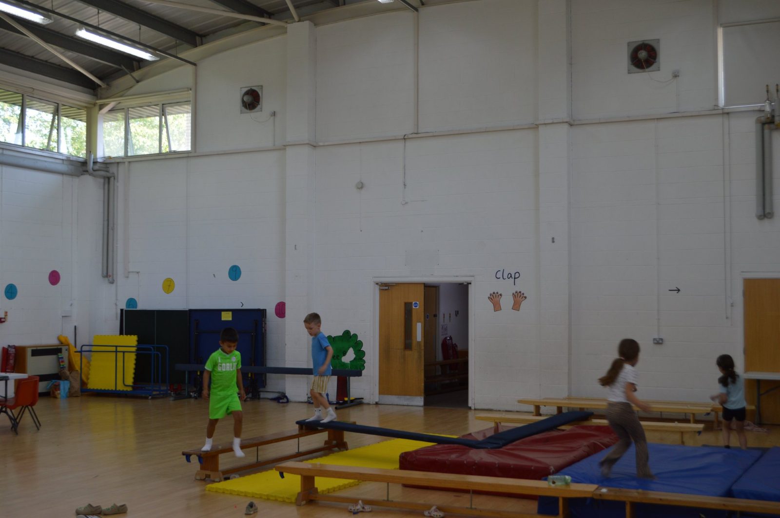 Children balancing along benches and beams in the school hall