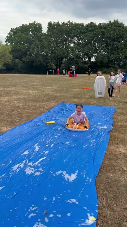 A child riding an inflatable down a water slide on the field